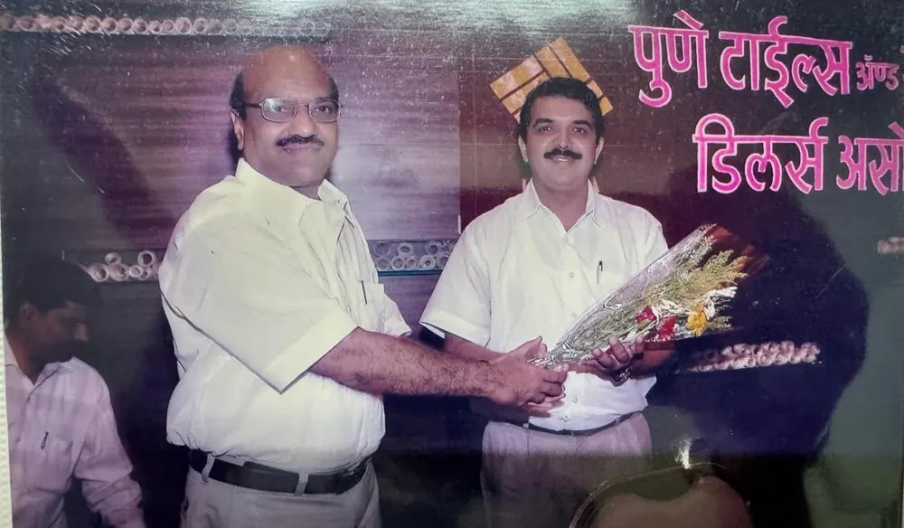 Two men exchanging a bouquet at a Pune Tiles and Sanitaryware Dealers Association event