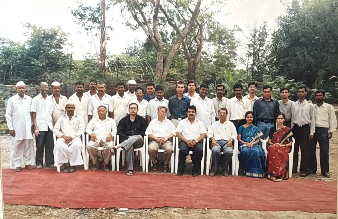 A large group photo taken outdoors, with people seated in front and standing in a row behind